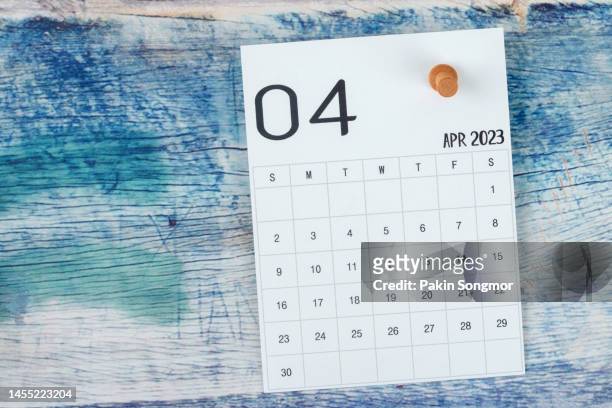 calendar desk 2023: april is the month for the organizer to plan and deadline with a push pin on a blue wooden background. - push pin stockfoto's en -beelden
