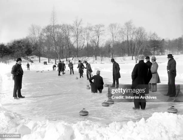 Group of men gather on a frozen pond to enjoy the sport of curling, in Central Park, New York, early twentieth century.