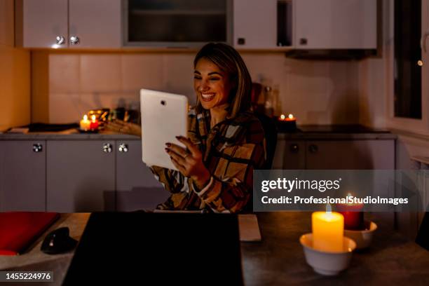 durante una crisi elettrica, una giovane donna sta lavorando a casa usando un tablet digitale. - candle light foto e immagini stock