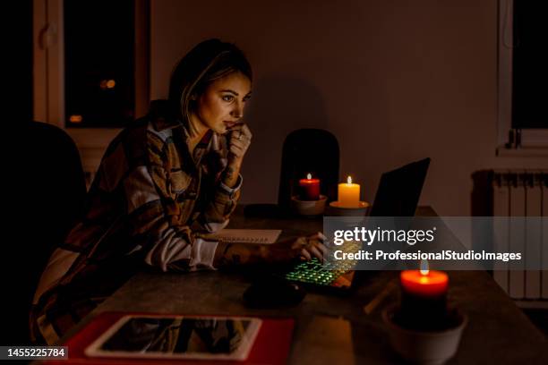 a woman is working at home during blackout time during an energetic crisis. - blackout stock pictures, royalty-free photos & images