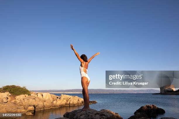 beautiful woman opening her arms towards the sun. - arm sun beach stock-fotos und bilder