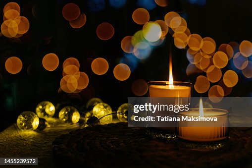 Two burning candles in the dark, a garland in the background. New year, Christmas, holiday concept. Two burning candles in the dark, a garland in the background. New year, Christmas, holiday concept.