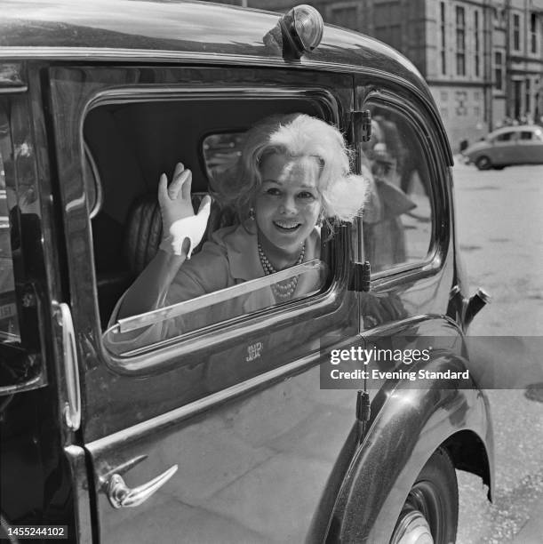 Hungarian actress Eva Gabor waving from a taxi window on July 20th, 1960.