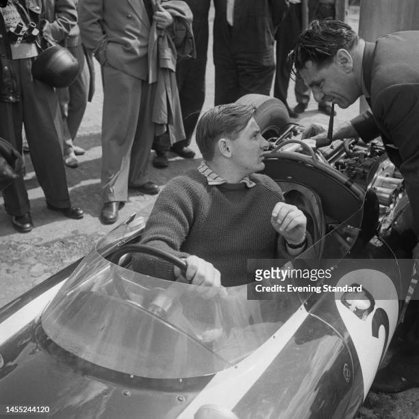 New Zealand racing driver Bruce McLaren sitting in his Cooper T53 Climax car and talking to John Cooper of the Cooper car company at the British...