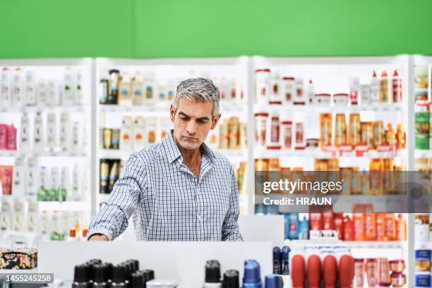 mature man searching for medicine on display rack in pharmacy - medicare supplement stock pictures, royalty-free photos & images