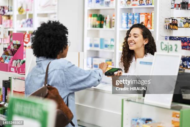 female customer making payment using contactless credit card - chemist shop stock pictures, royalty-free photos & images