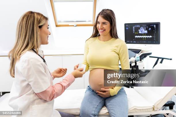 ärztin gibt schwangeren frauen während des termins pillen - gynaecologist stock-fotos und bilder