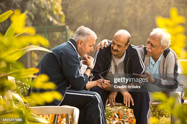 depressed old man with friends sitting at park - agony in the garden stockfoto's en -beelden