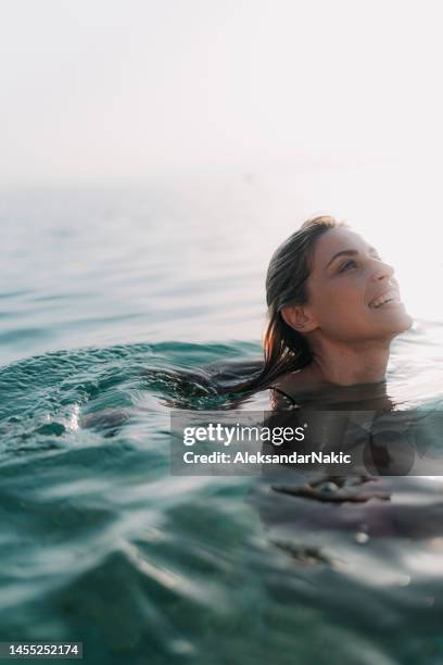 mujer joven nadando en el agua tranquila del mar - floating on water fotografías e imágenes de stock