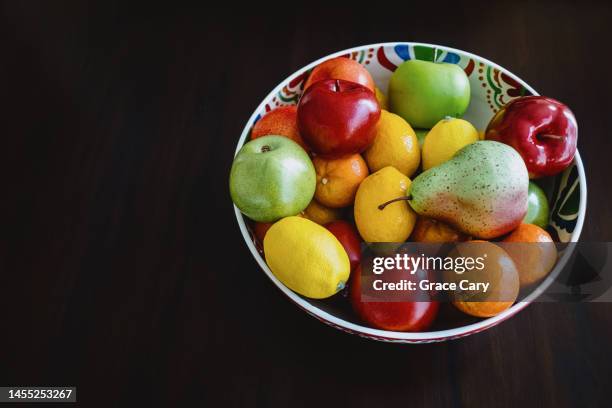 bowl of decorative fruit on dining table - fruit bowl stock pictures, royalty-free photos & images