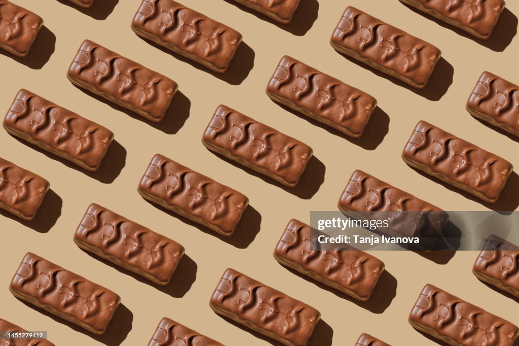 Pattern of chocolate bars on beige background. Flat lay, top view