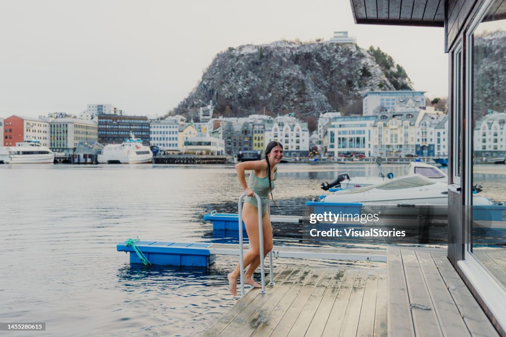 Donna felice che fa il bagno in mare durante l'inverno ad Alesund, Norvegia
