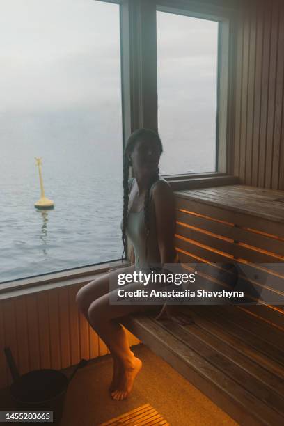 donna che contempla il tempo della sauna con vista sul mare in norvegia - sauna winter foto e immagini stock