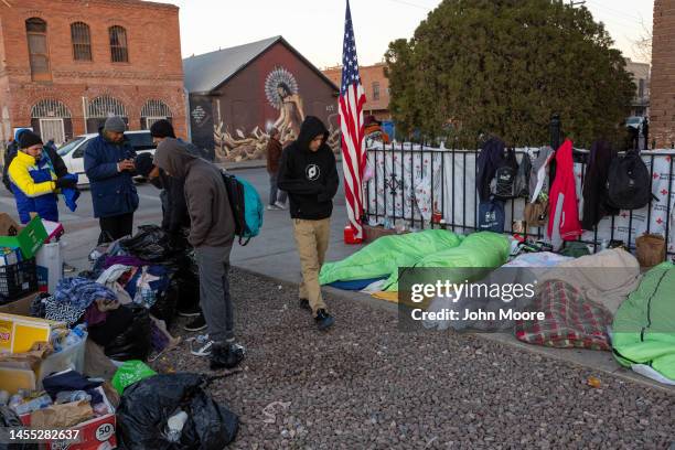 Immigrants sleep on the sidewalk as others look through donated clothing near a migrant shelter on January 9, 2023 in El Paso, Texas. President Joe...