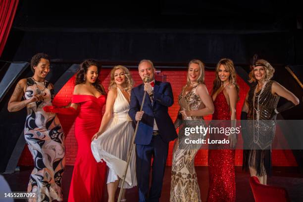 handsome male singer on stage surrounded by a group of beautiful women - celebrity cabaret stock pictures, royalty-free photos & images