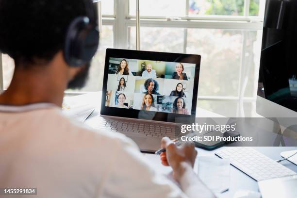 over-the-shoulder view unrecognizable male college student attending online class - working behind laptop stockfoto's en -beelden