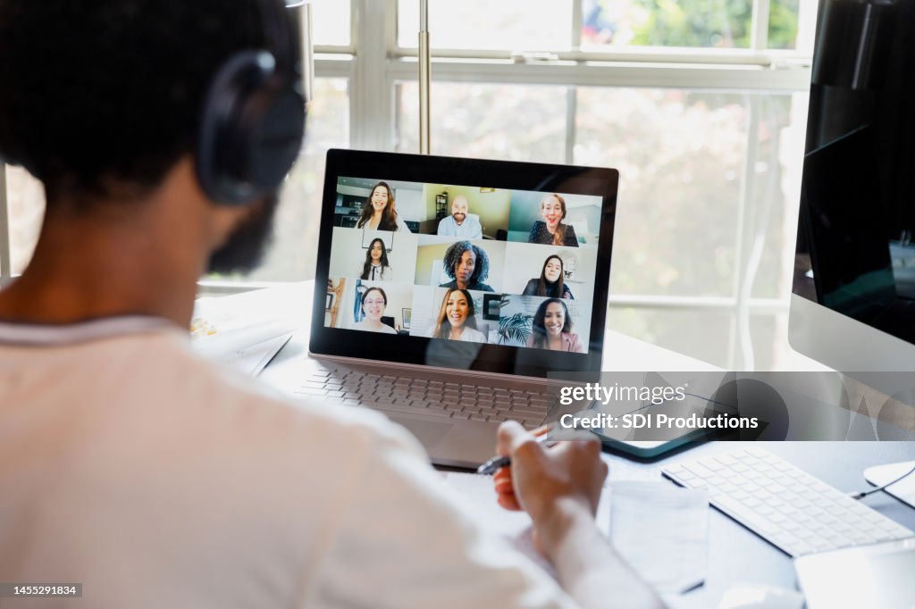 Over-the-shoulder view unrecognizable male college student attending online class