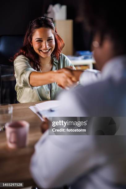 young woman shaking hands with a manger at the beginning of a job interview - manger stock pictures, royalty-free photos & images