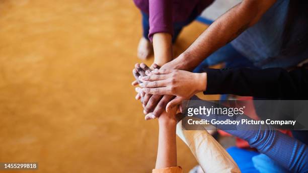 diverse businesspeople standing with their hands together in an office - togetherness hands stock pictures, royalty-free photos & images