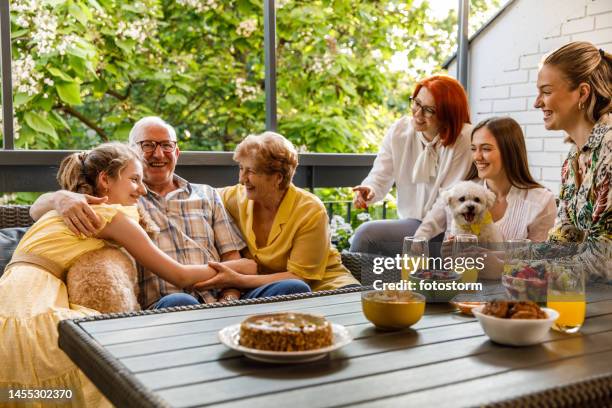 mehrgenerationenfamilie mit verbindenden momenten während einer feier auf dem balkon - familienfeier stock-fotos und bilder