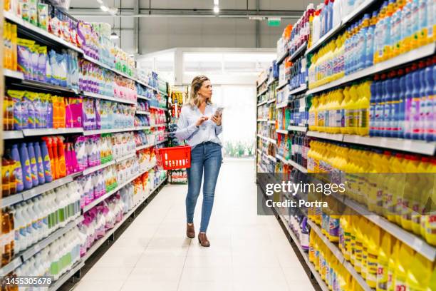 woman customer with mobile phone buying groceries in store - förvaringsställ bildbanksfoton och bilder