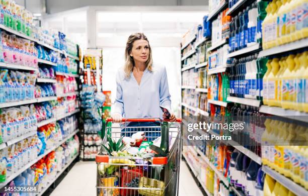 mature woman customer buying grocery in supermarket - shopping trolley supermarket stock pictures, royalty-free photos & images