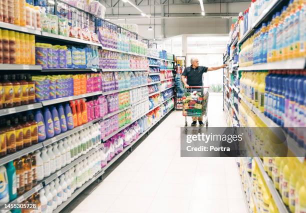 uomo anziano con il carrello della spesa nella corsia del supermercato - detersivi foto e immagini stock