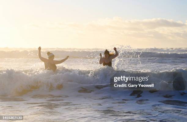 winter swimming in the sea at sunrise - people in mid air stock pictures, royalty-free photos & images