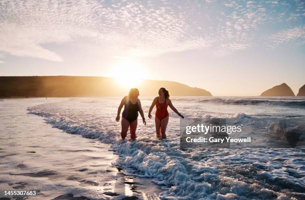 winter swimming in the sea at sunset - cornwall coast stock pictures, royalty-free photos & images