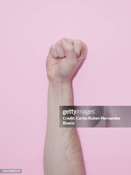 man's raised fist in protest on a pink background - fist raised stock pictures, royalty-free photos & images