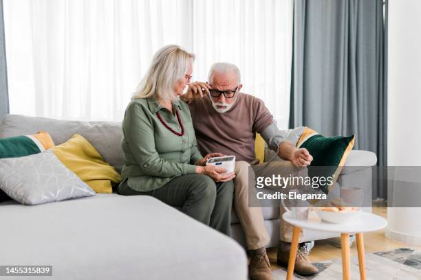 senior couple checking blood pressure at home. wife examining blood pressure on her husband's arm with a blood pressure monitor - altitude sickness stock pictures, royalty-free photos & images