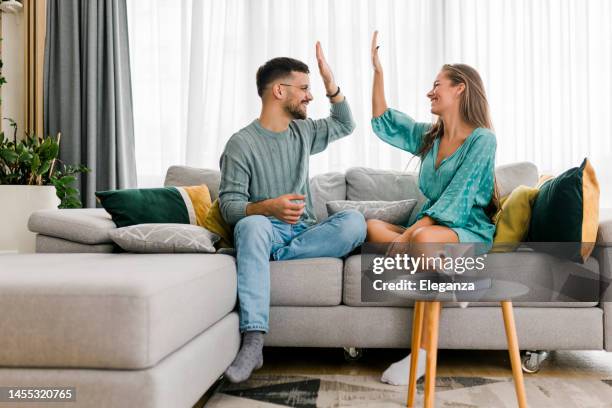 aufnahme eines glücklichen jungen paares, das ein high five teilt - high five stock-fotos und bilder