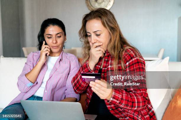 stressed upset woman holding bank card and being surprised - hacker computer stockfoto's en -beelden