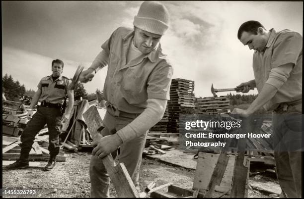 As part of the McNeil Island Prison's Work Ethic Program, Craig Bettnke and John Glover recycle wooden pallets as Correctional Officer Ron Carpenter...