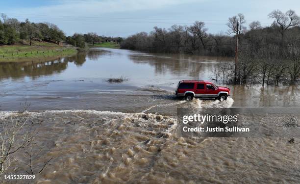 In an aerial view, a truck drives through a flooded section of road on January 09, 2023 in Forestville, California. The San Francisco Bay Area...