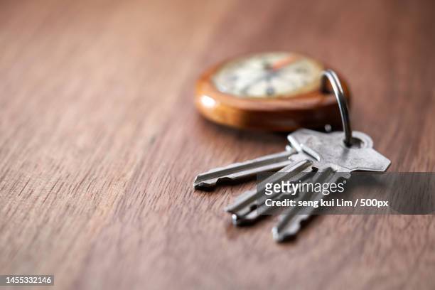 house key and compass key ring against wood background,malaysia - key ring isolated stockfoto's en -beelden