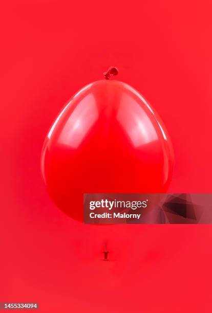 balloon floating over a pin. symbolizing inflation - safety pin stockfoto's en -beelden