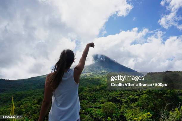 woman standing and pointing to the top of the volcano,arenal volcano,costa rica - arenal volcano stockfoto's en -beelden