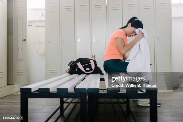 woman sitting in locker room after working out - künstlergarderobe stock-fotos und bilder
