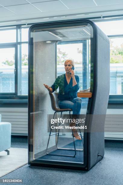 businesswoman talking on mobile phone in soundproof cabin at office - office cabin ストックフォトと画像