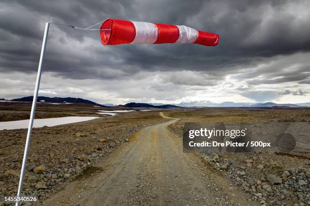 striped windbag and mountain gravel road with dark clouds,kaldidalur - kaldidalur stock pictures, royalty-free photos & images