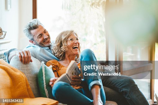 Cheerful mature couple sitting on sofa at home Cheerful mature couple sitting on sofa at home