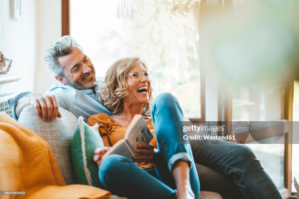 Cheerful mature couple sitting on sofa at home