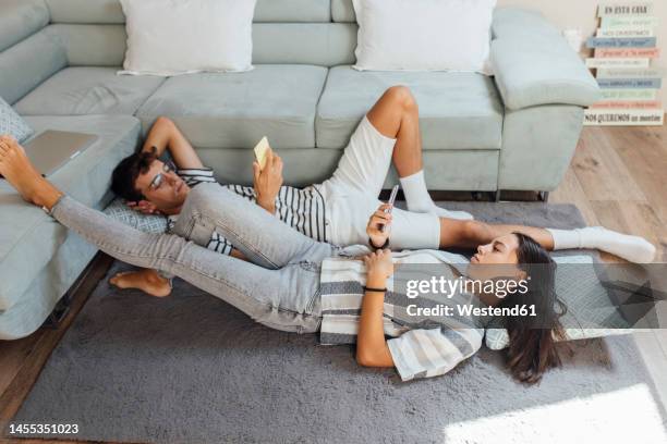 girl and boy using smart phone lying on carpet in living room at home - lying on back girl on the sofa stock pictures, royalty-free photos & images