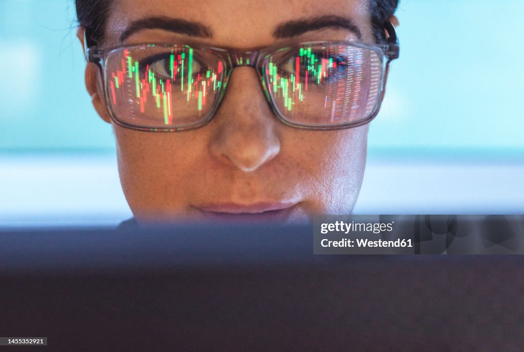 Stockbroker analyzing financial stock market with reflection on eyeglasses