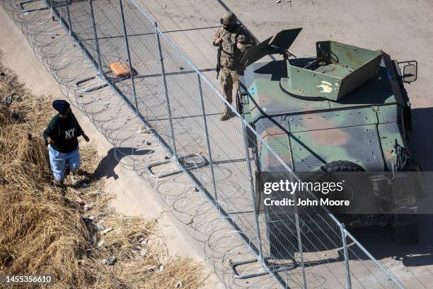 An immigrant passes Texas National Guard soldiers at the U.S.Mexico border on January 09, 2023 in El Paso, Texas. President Joe Biden visited El Paso...