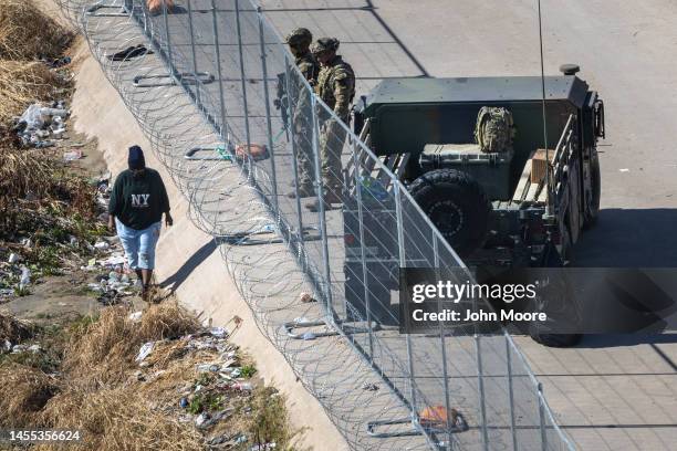 An immigrant passes Texas National Guard soldiers at the U.S.Mexico border on January 09, 2023 in El Paso, Texas. President Joe Biden visited El Paso...