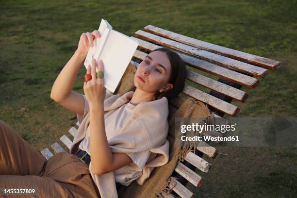 young woman reading book on deck chair - deckchair book stock pictures, royalty-free photos & images
