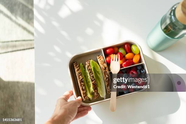 hand of woman holding lunch box with healthy food on table - lunch bag stock pictures, royalty-free photos & images