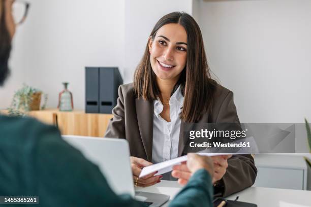 candidate giving resume to recruiter at desk in workplace - apprentice office stockfoto's en -beelden